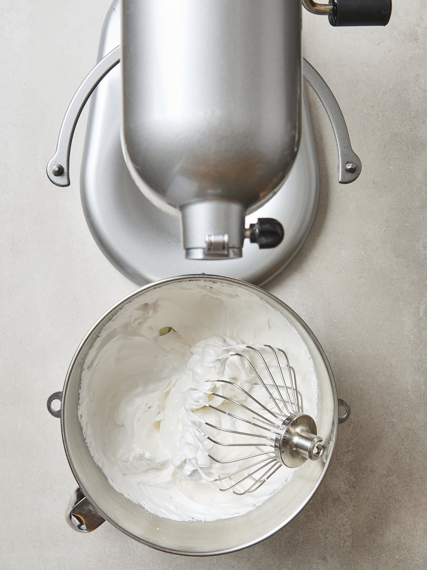 Whipped meringue topping in a bowl with a stand mixer.