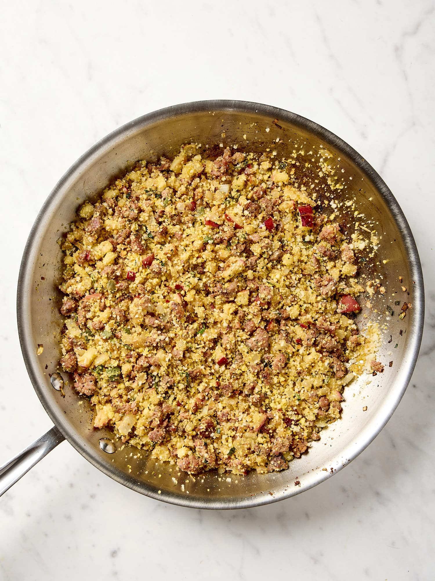 Skillet filled with sausage, apple, and herb filling for a turkey roulade.