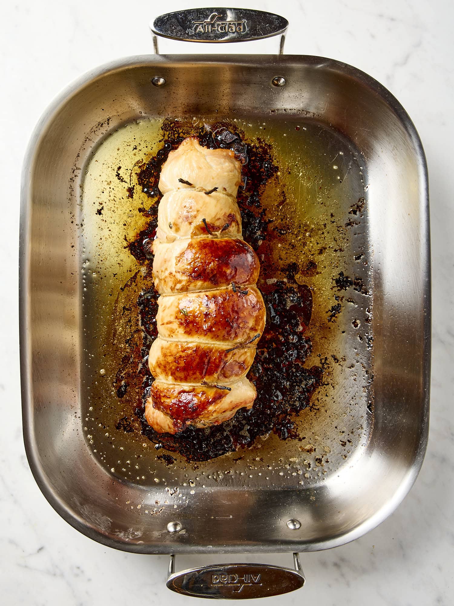 Fully cooked turkey breast with golden skin in a roasting pan.