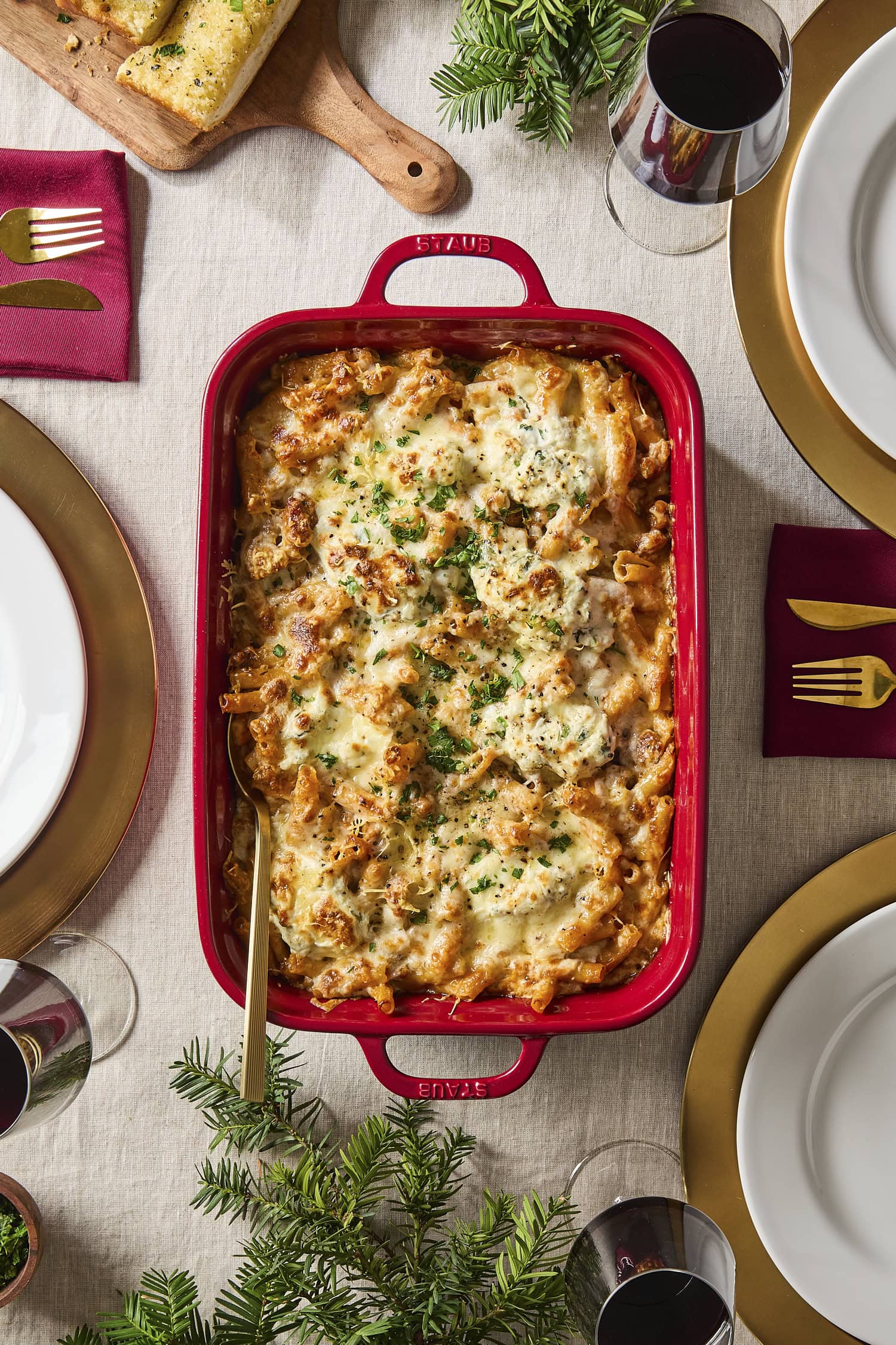 Serving of baked ziti on a table ready for the holidays with herb garnish on top.