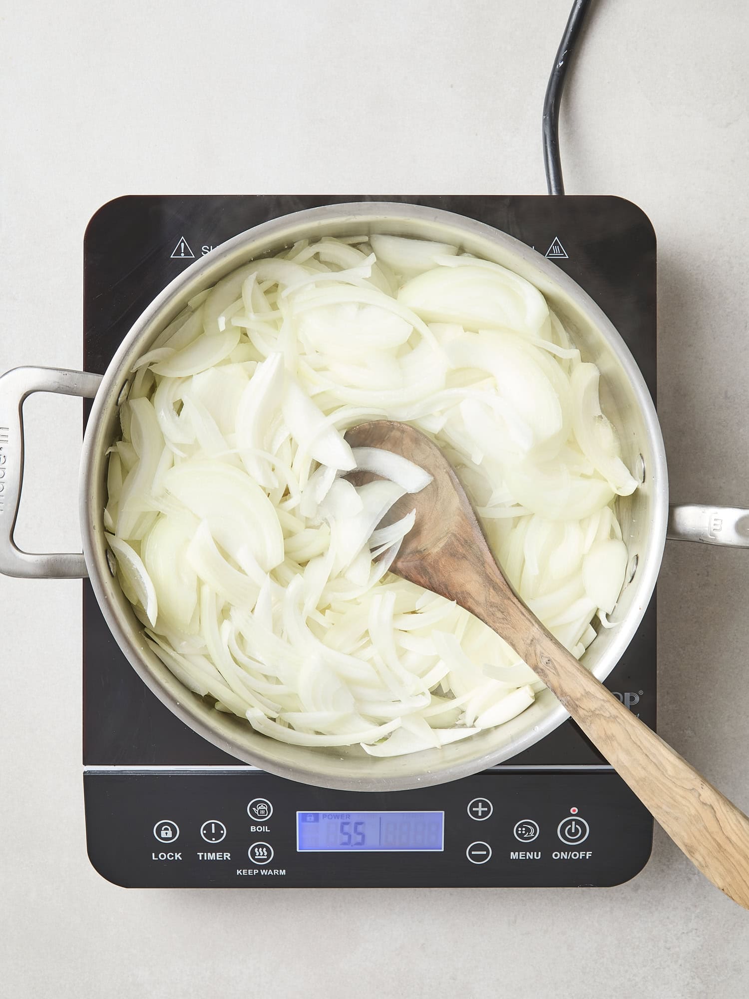 Pan cooking raw onions over heat.