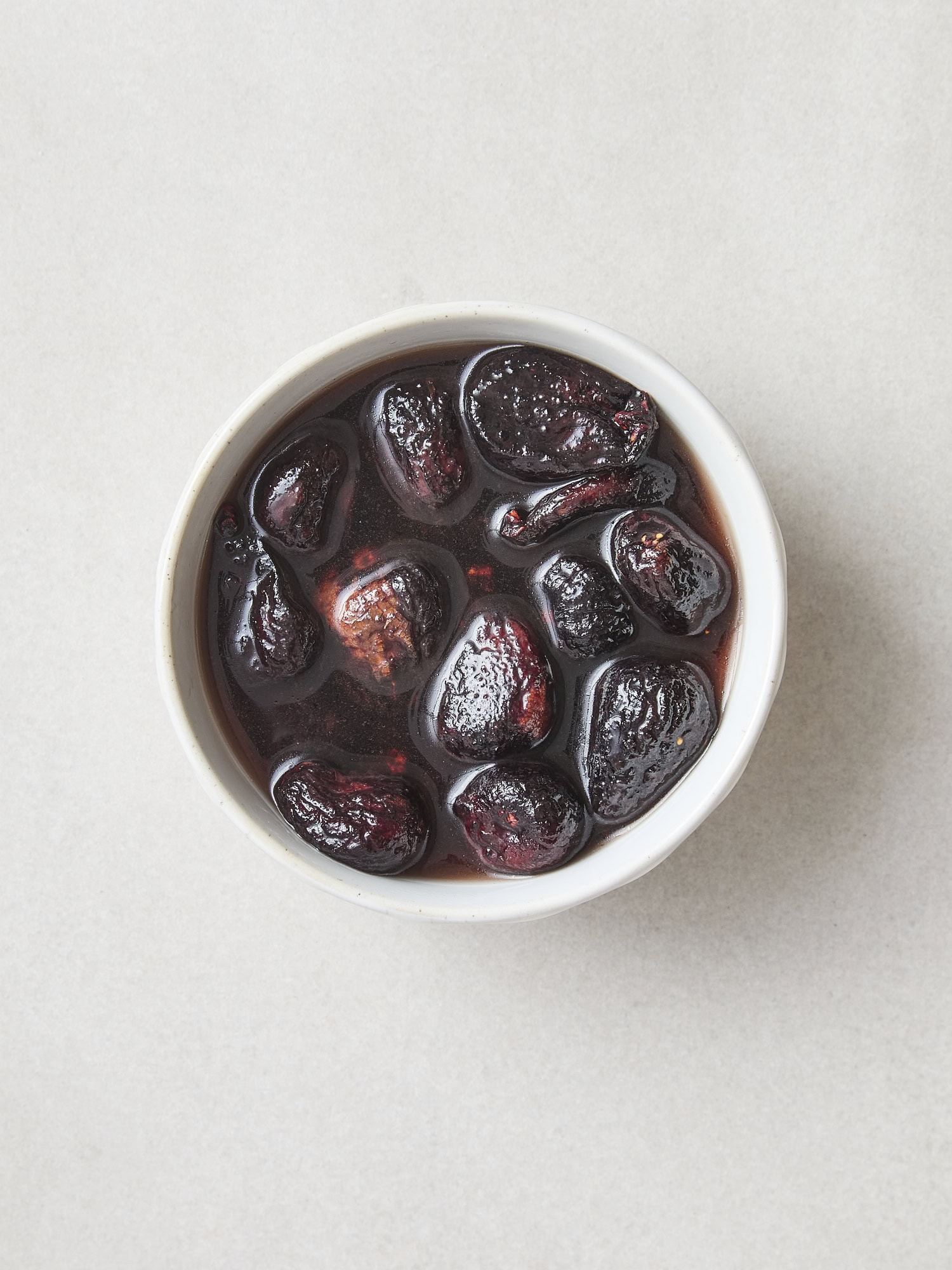 Dried figs soaking in sherry in a white bowl.