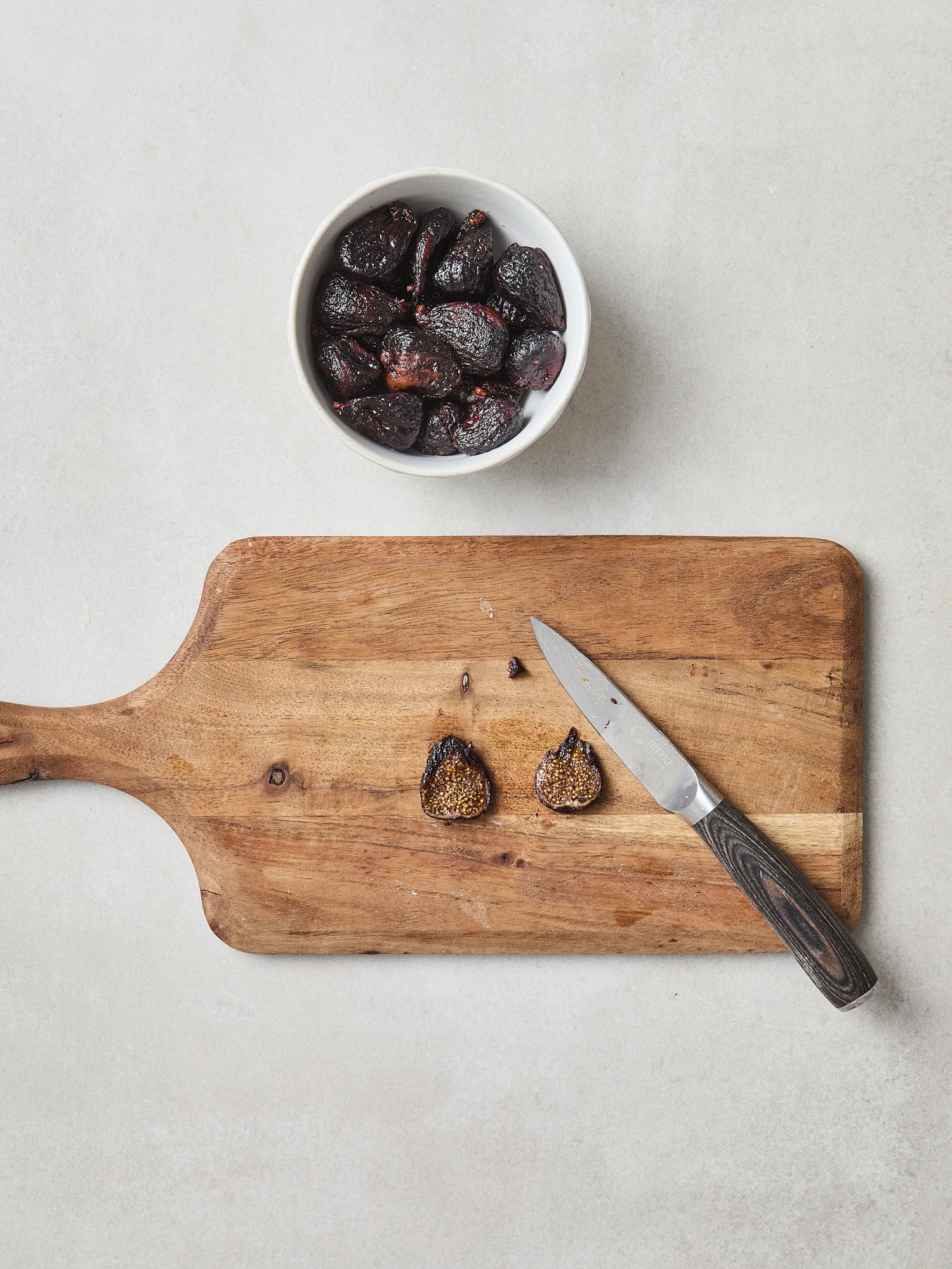 Sliced figs on a cutting board with more in a bowl to the side.