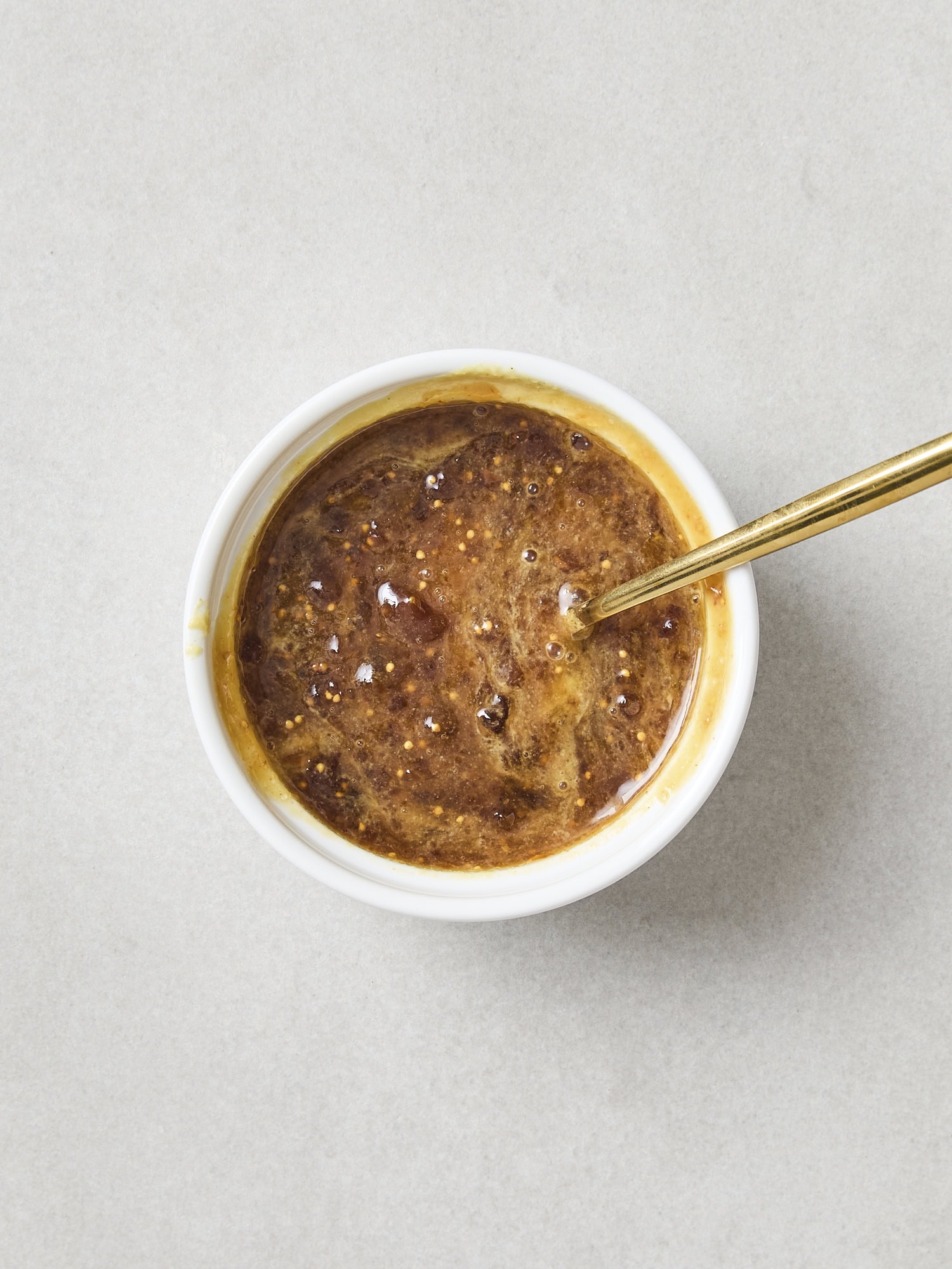 Small bowl filled with mixture of mustard and fig preserved.