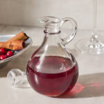 Glass container with red-colored cranberry simple syrup.