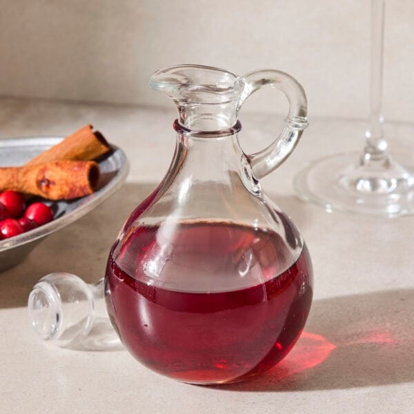 Glass container with red-colored cranberry simple syrup.