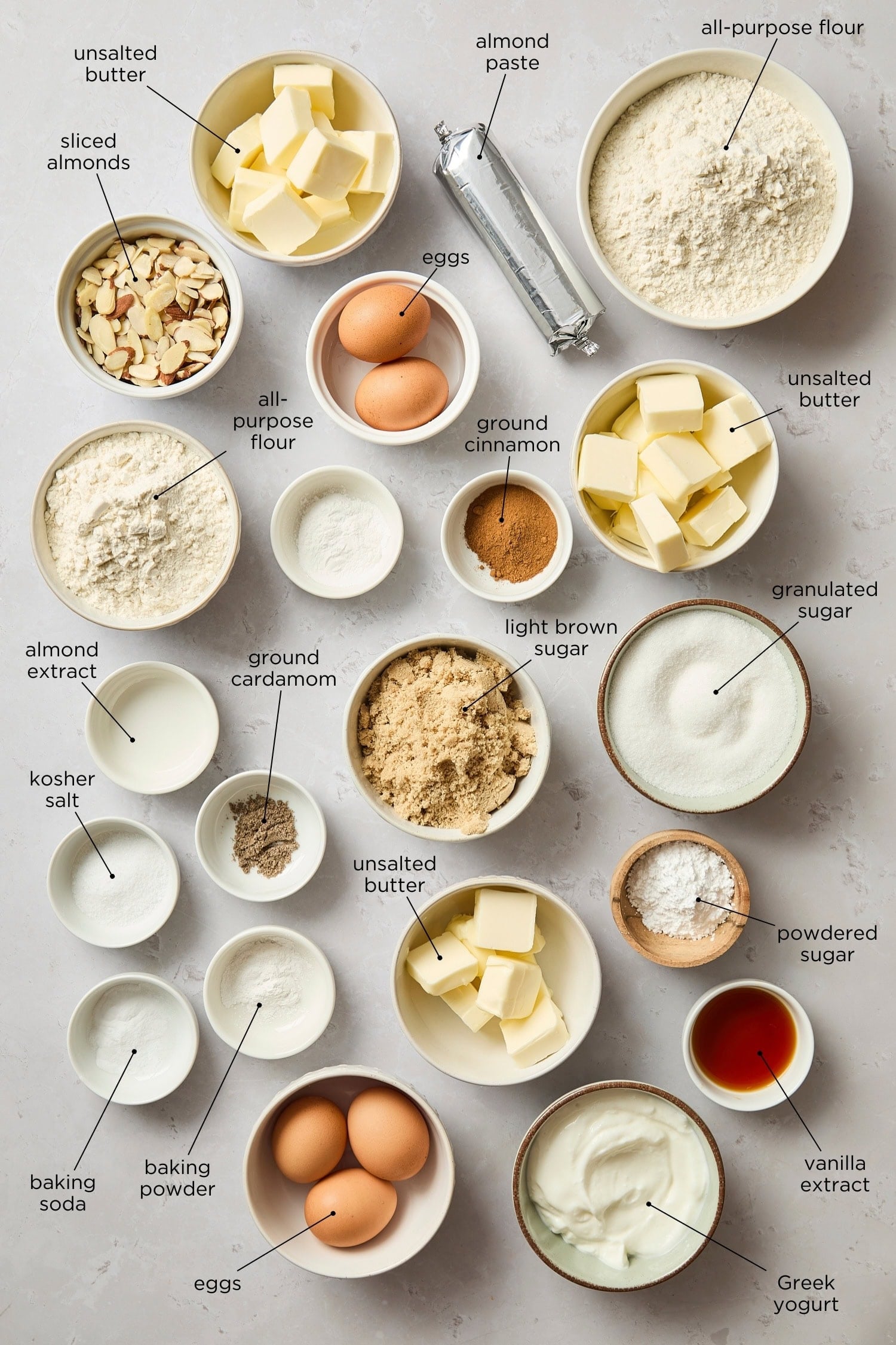 Concrete surface with ingredients for a frangipane coffee cake including almond paste, sugar, flour, butter, and more.