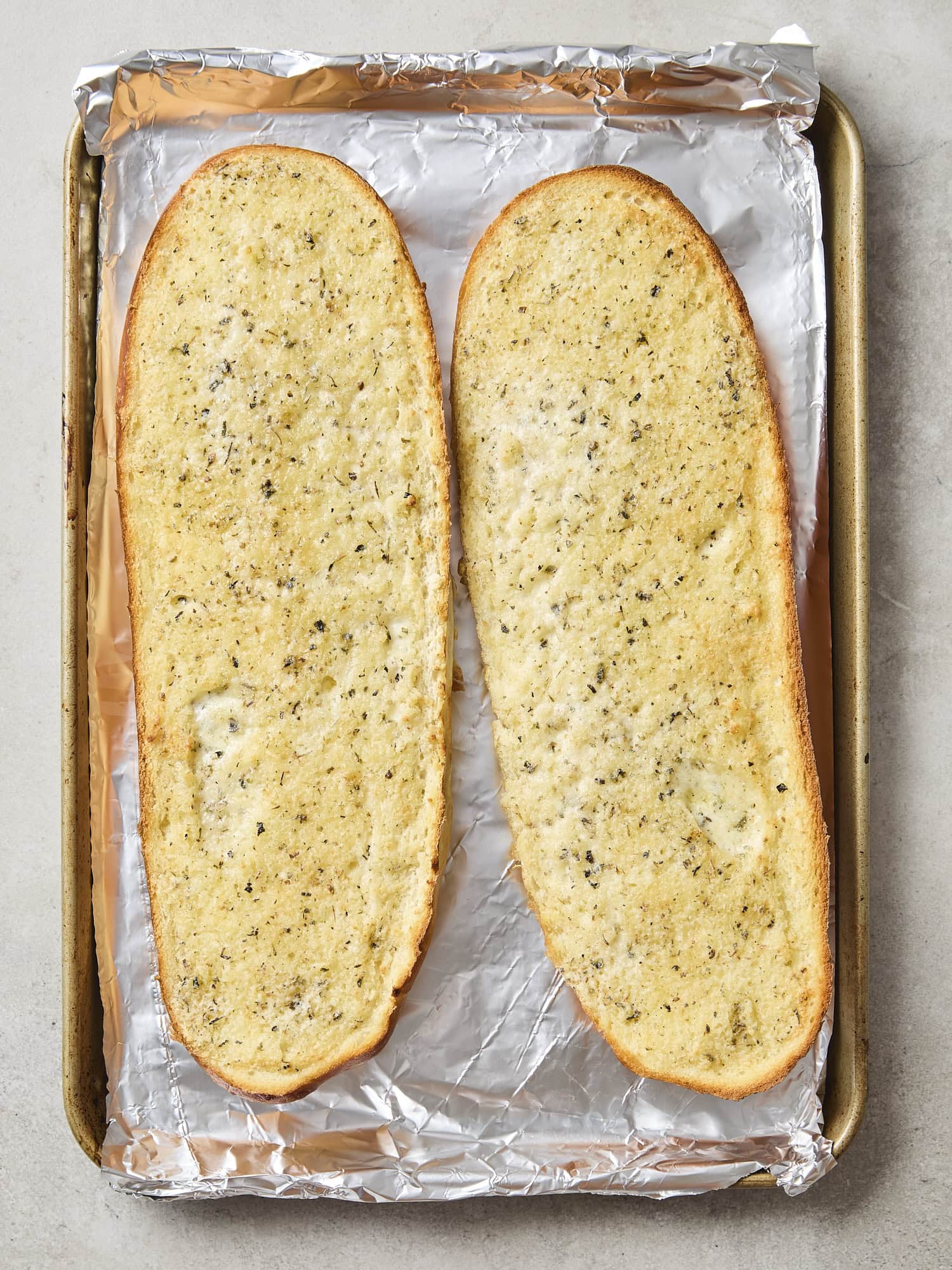 Two halves of garlic bread after being baked in the oven.