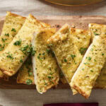 Garlic bread topped with freshly chopped parsley.