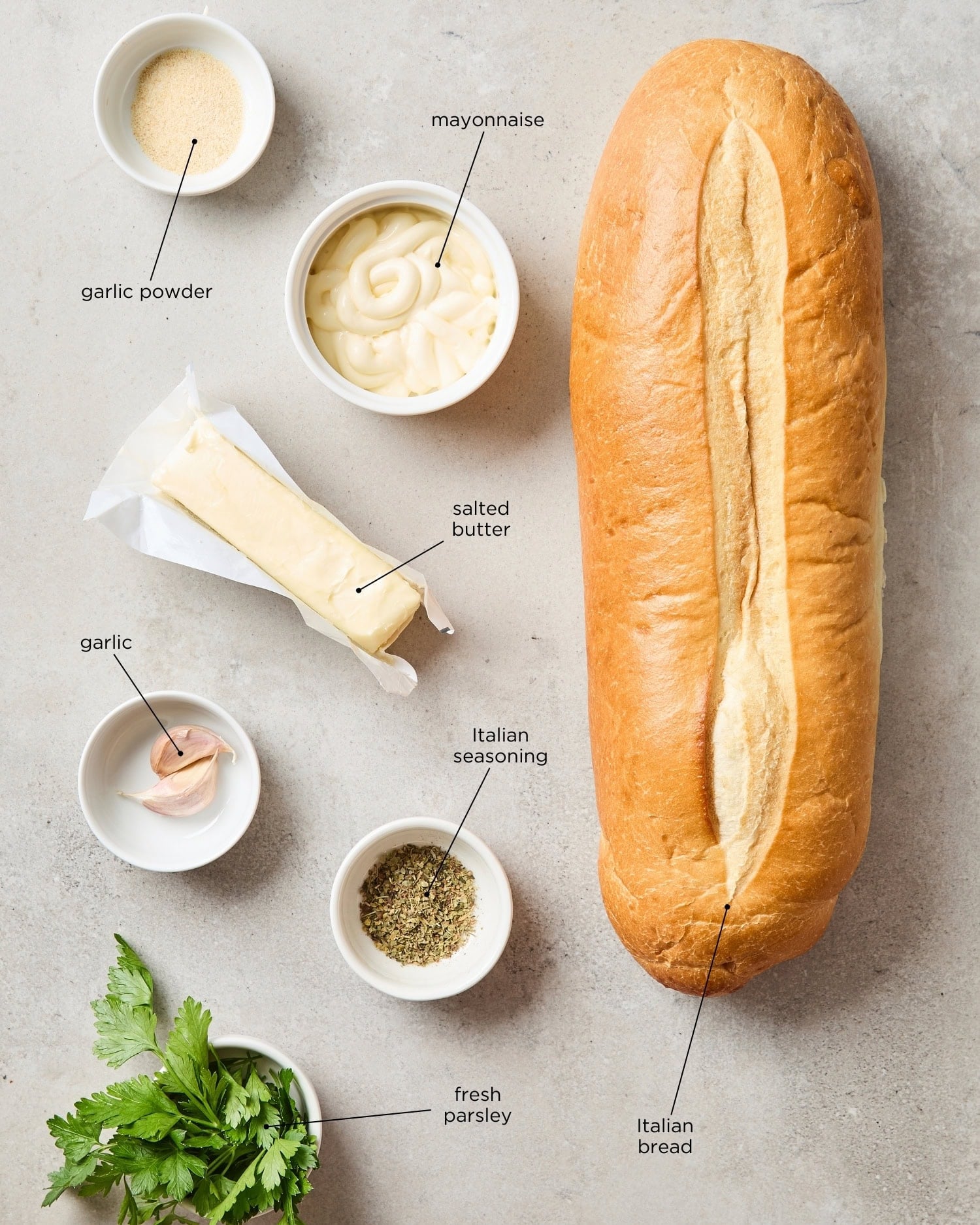 Concrete surface with ingredients needed for garlic bread.