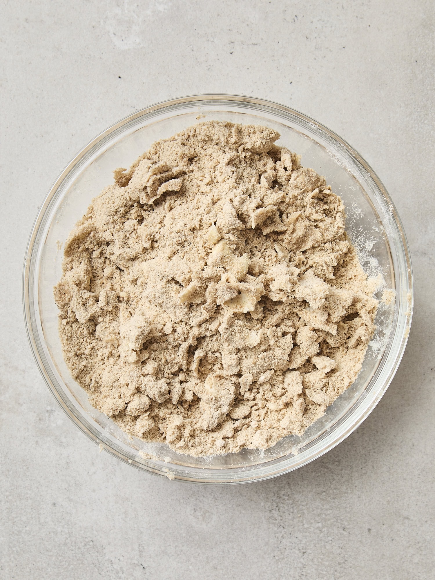 Mixture of cardamom crumb topping for pistachio muffins in a glass bowl.