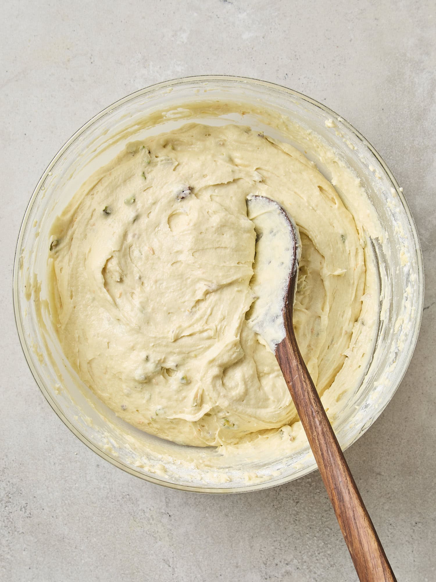 Mixed pistachio muffin batter in glass bowl.