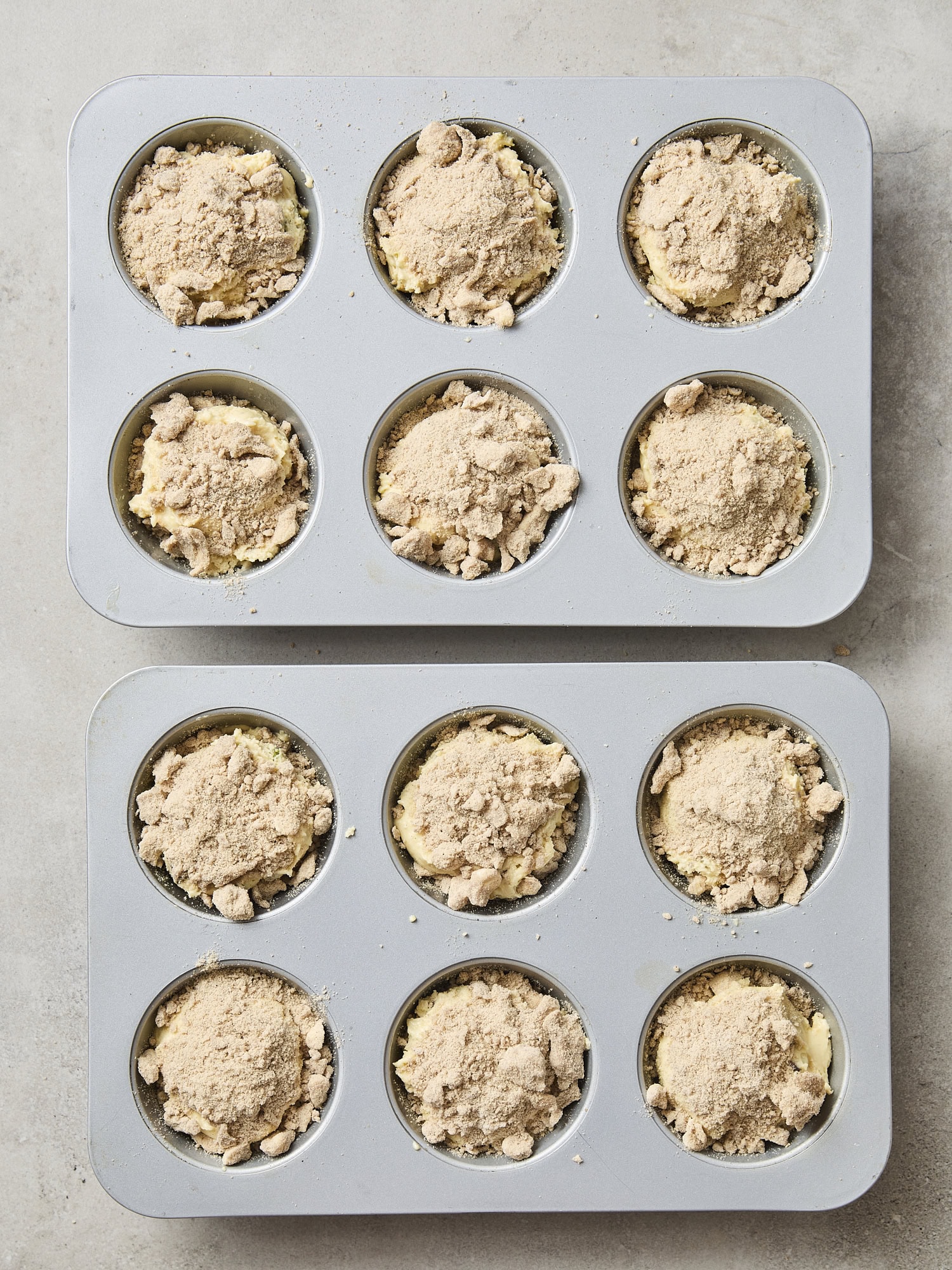 Crumb topping on top of batter in muffins tins.