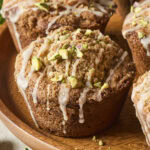 Bakery-style pistachio muffins with vanilla glaze and chopped pistachios on top.