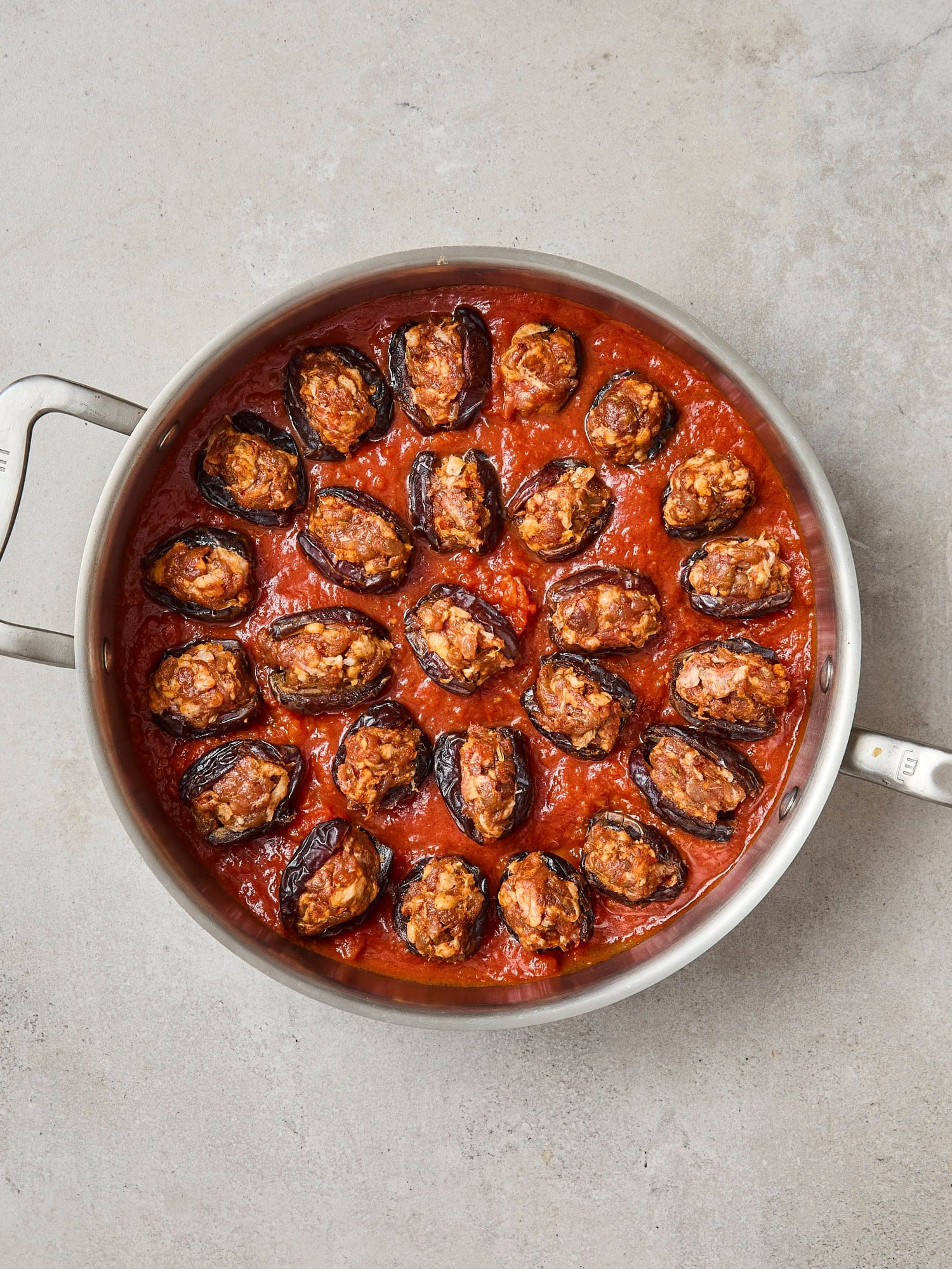 Pan filled with marinara sauce and stuffed dates before being baked.