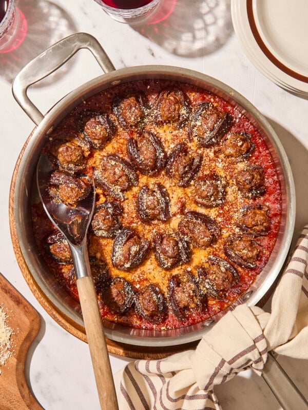 Baked stuffed dates in a round skillet with Parmesan cheese sprinkled on top.