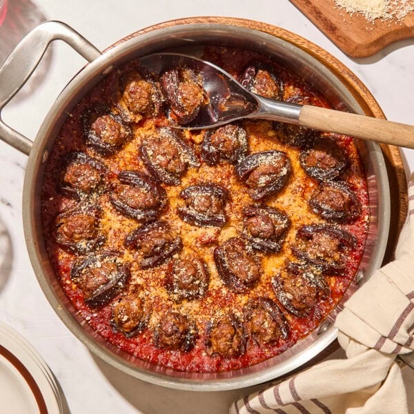 Skillet filled with cooked stuffed dates with Parmesan cheese sprinkled over the top.