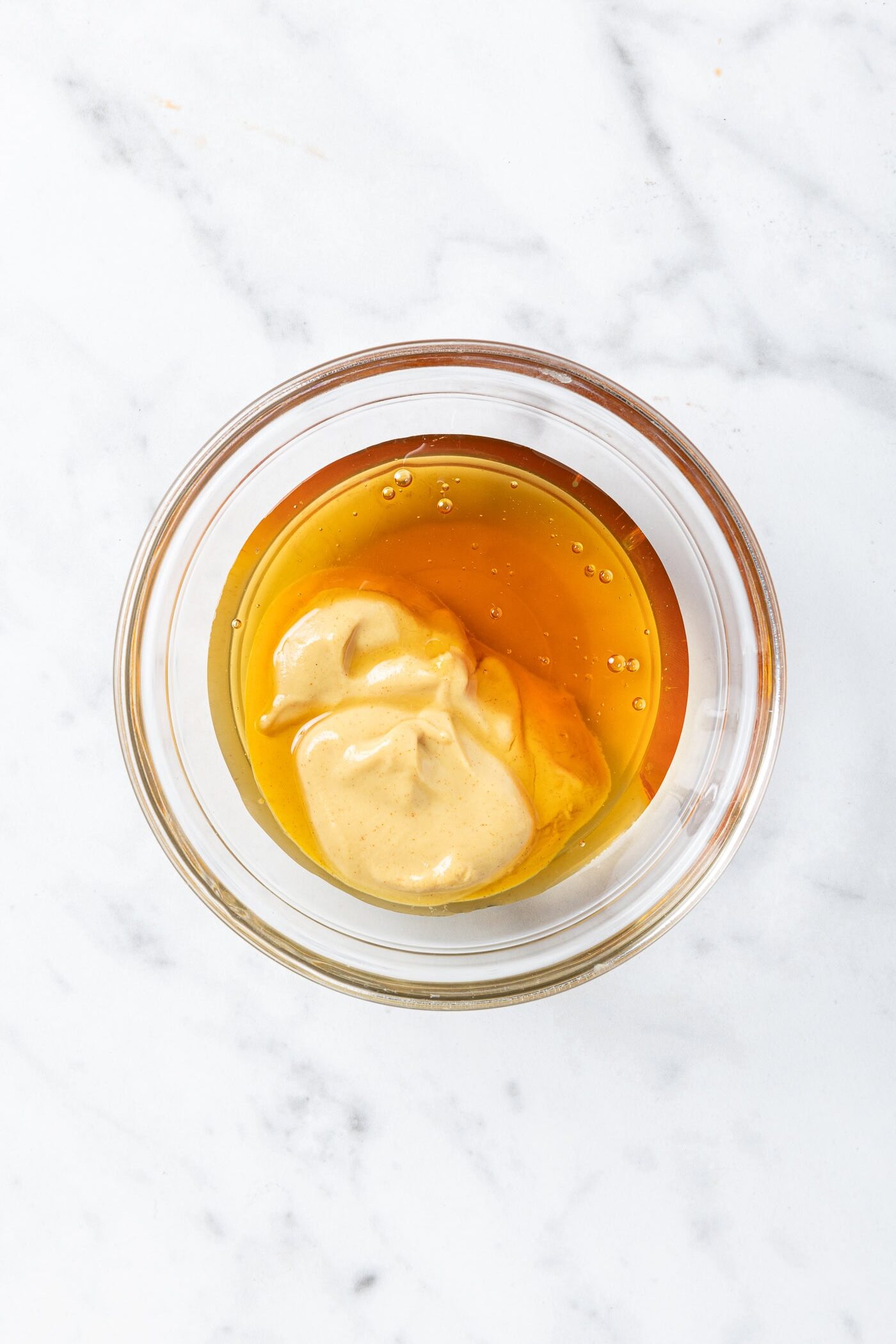 Equal parts Dijon mustard and honey in a bowl prior to being mixed.