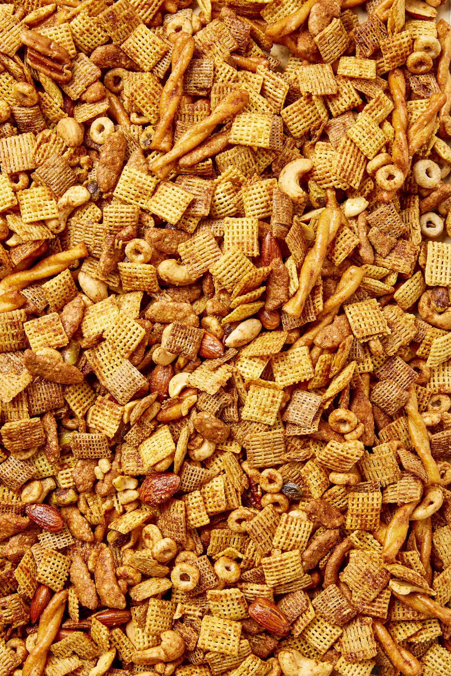 Party mix made with cereal, nuts, and pretzels, all with a buttery coating.