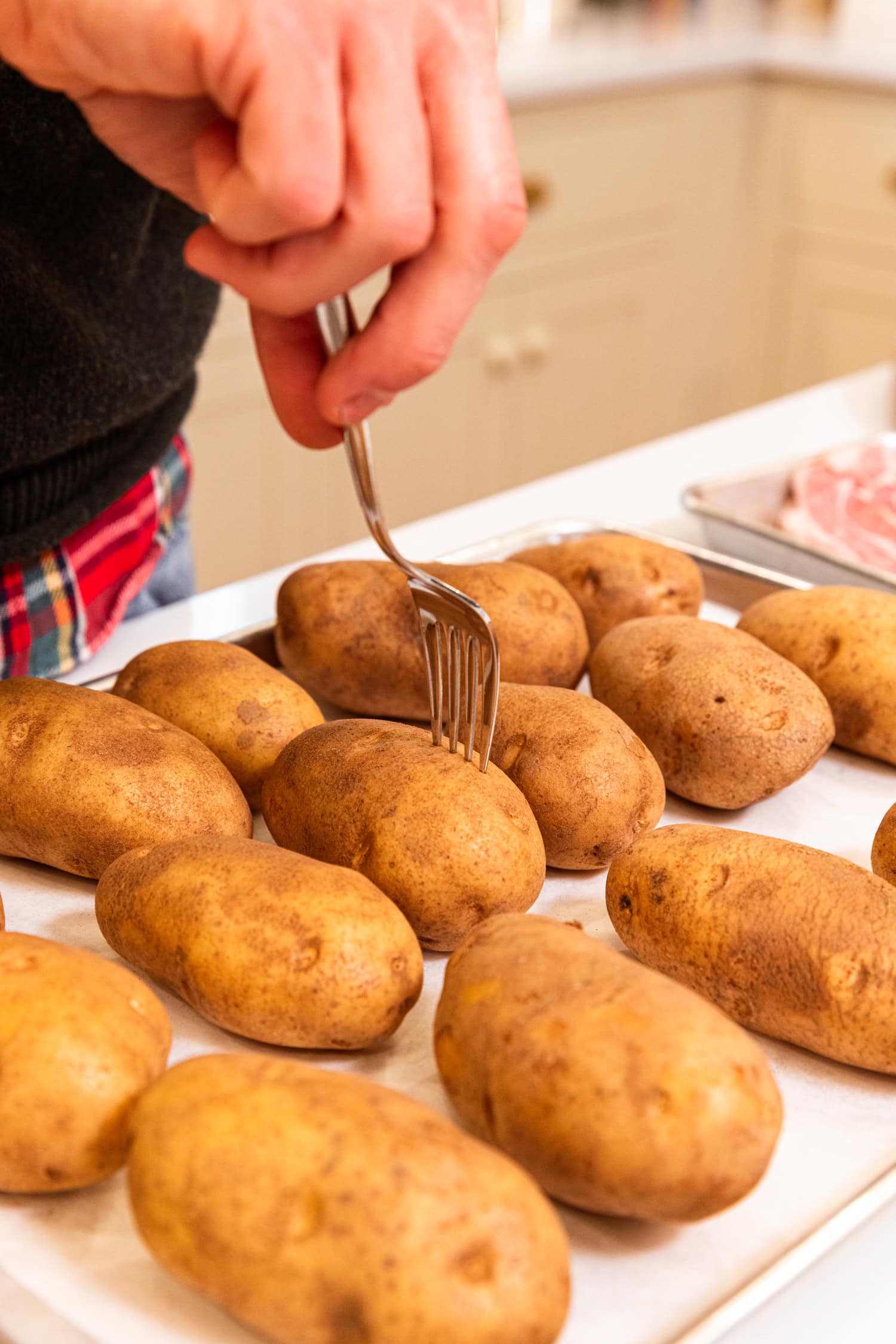 Fork pricking into potatoes to get them ready to bake.