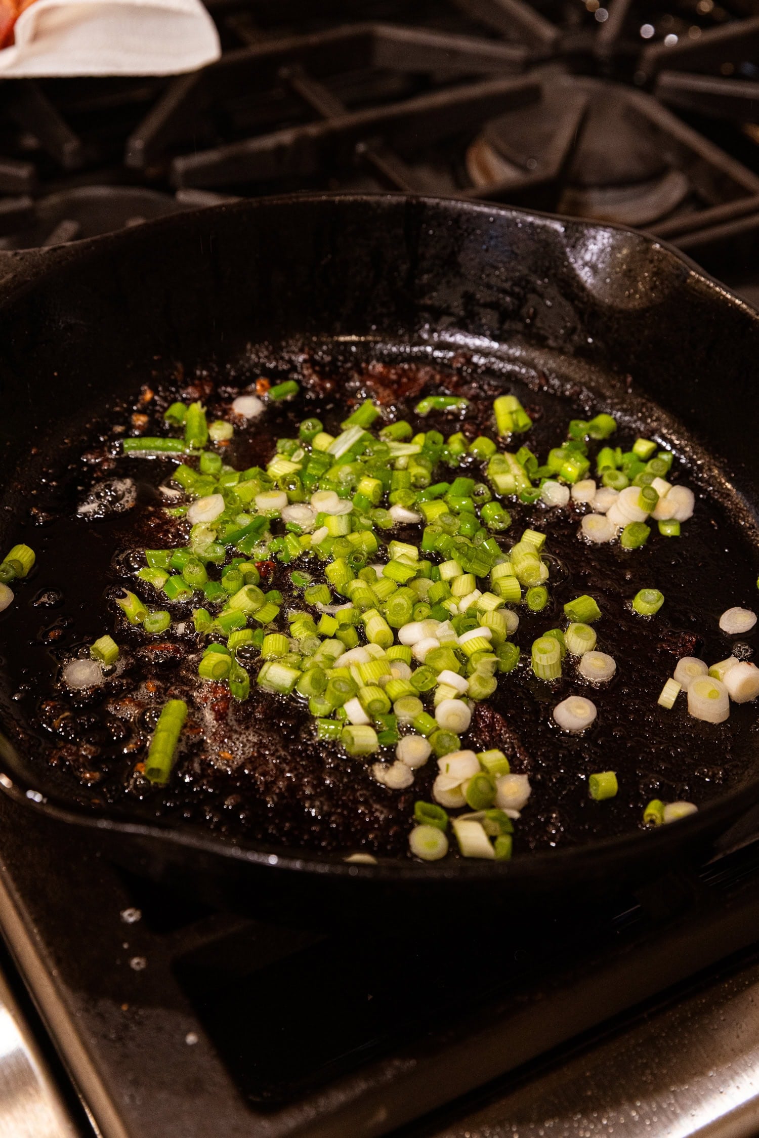 Skillet with chopped scallion cooking in oil.