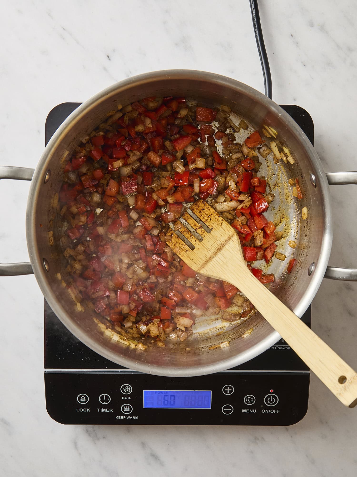 Aromatics in a pot with spices and wooden spatula.