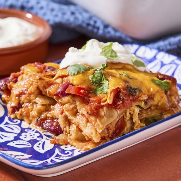Patterned plate with serving of chicken tortilla casserole topped with fresh cilantro.