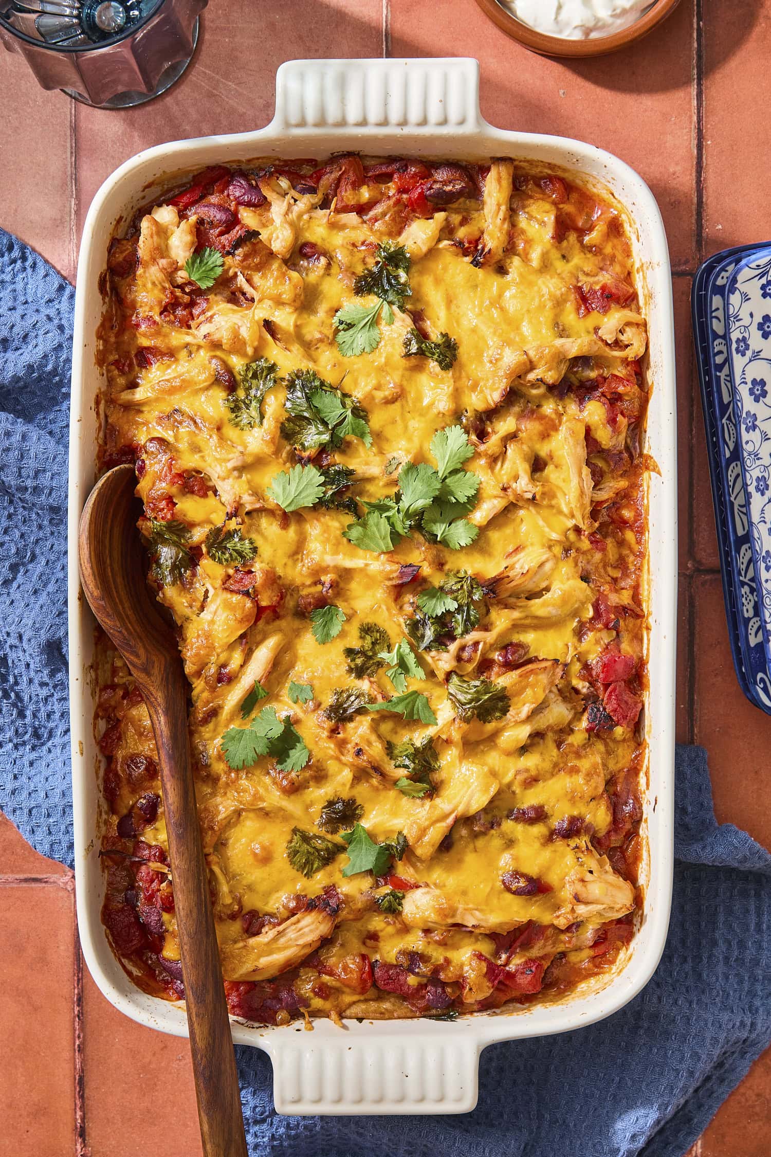Baking pan with baked chicken tortilla casserole with cheese and cilantro sprinkled on top.