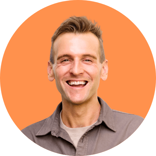 Kaleb Wyse smiling and standing in front of an orange background.