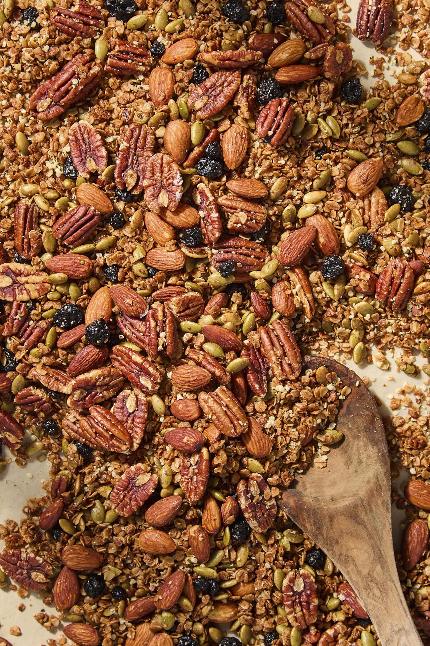 Spoon resting on homemade granola on a sheet pan.