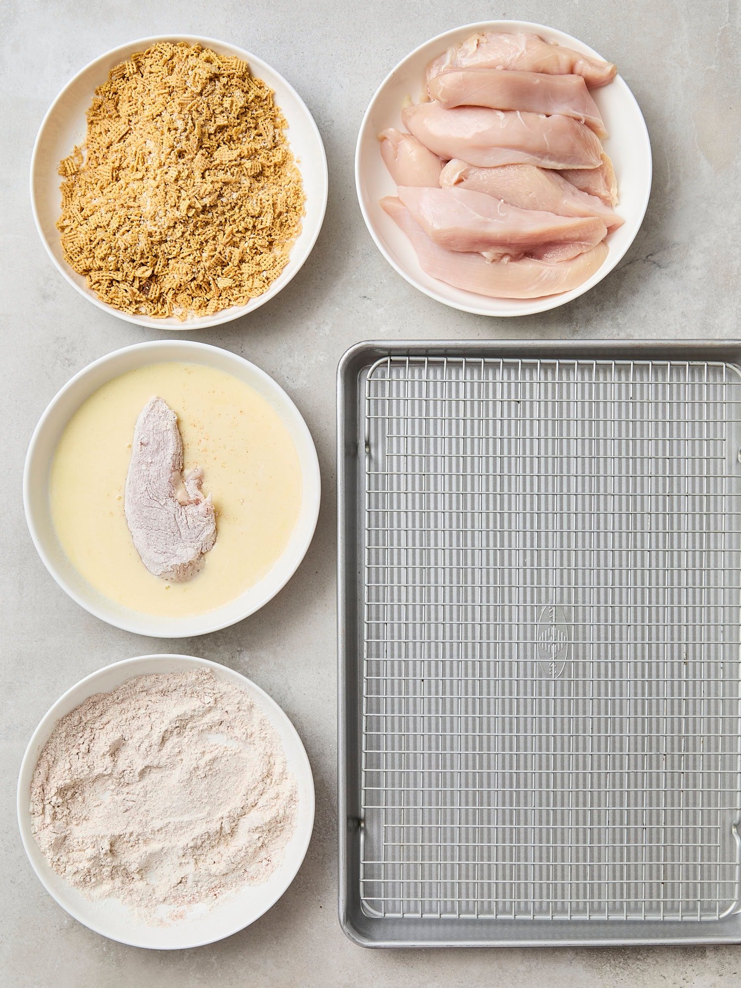 Wire baking rack with bowls for baked crispy chicken strips.