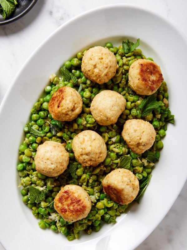 Plate filled with baked chicken meatballs with a pea mash underneath.