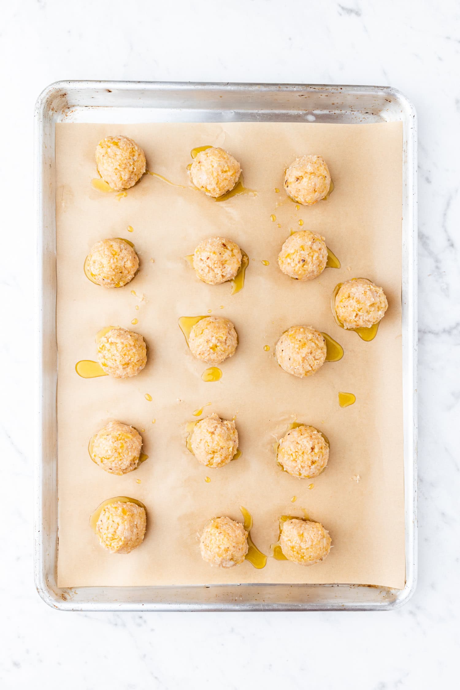 Chicken meatballs on sheet pan before baking in oven.