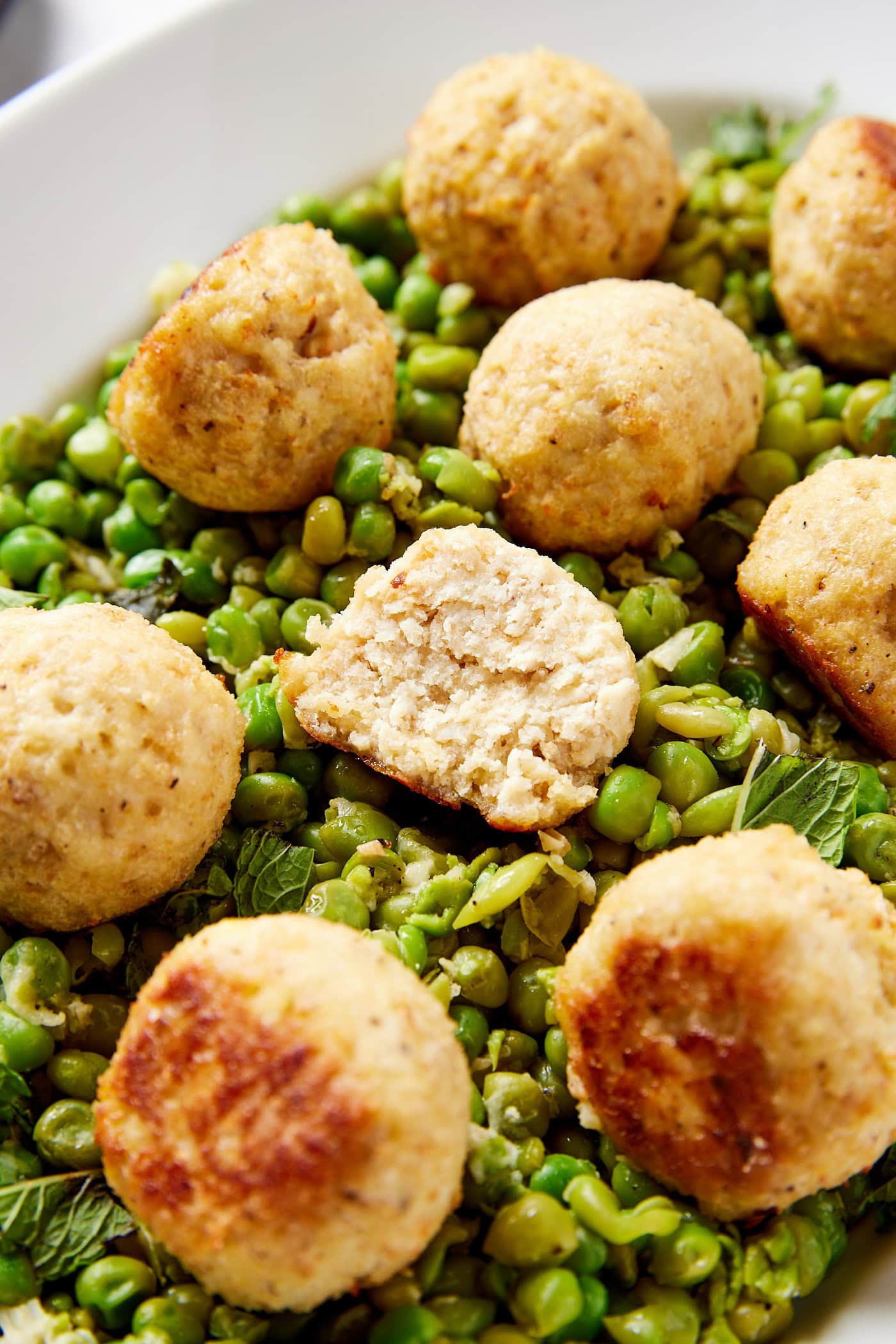 Chicken meatball with half eaten sitting on pea mash.