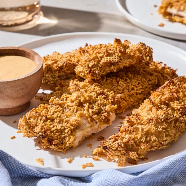 Chicken strips with crispy coating on plate with honey mustard sauce.