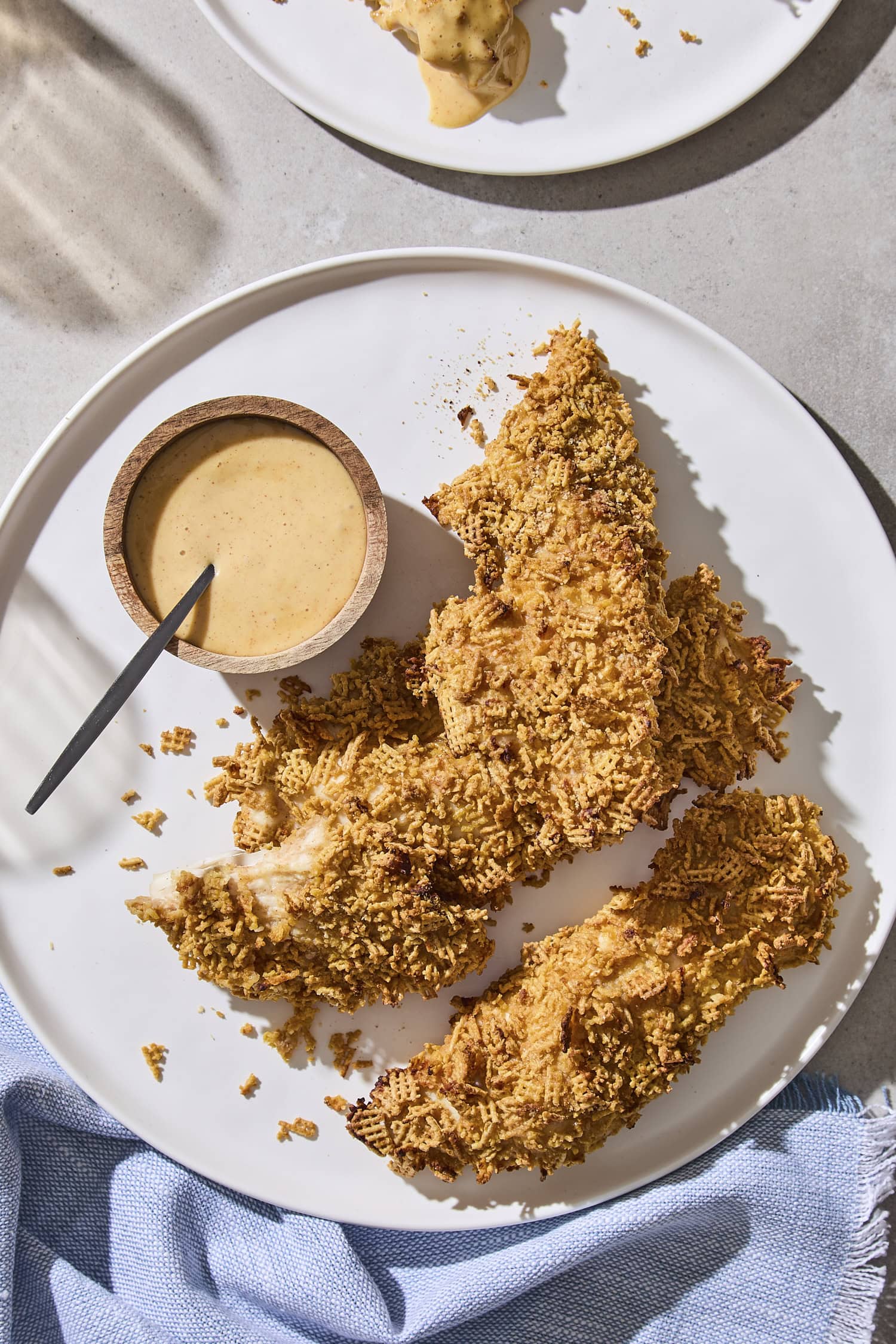 Plate with crispy chicken strips with honey mustard to dip.