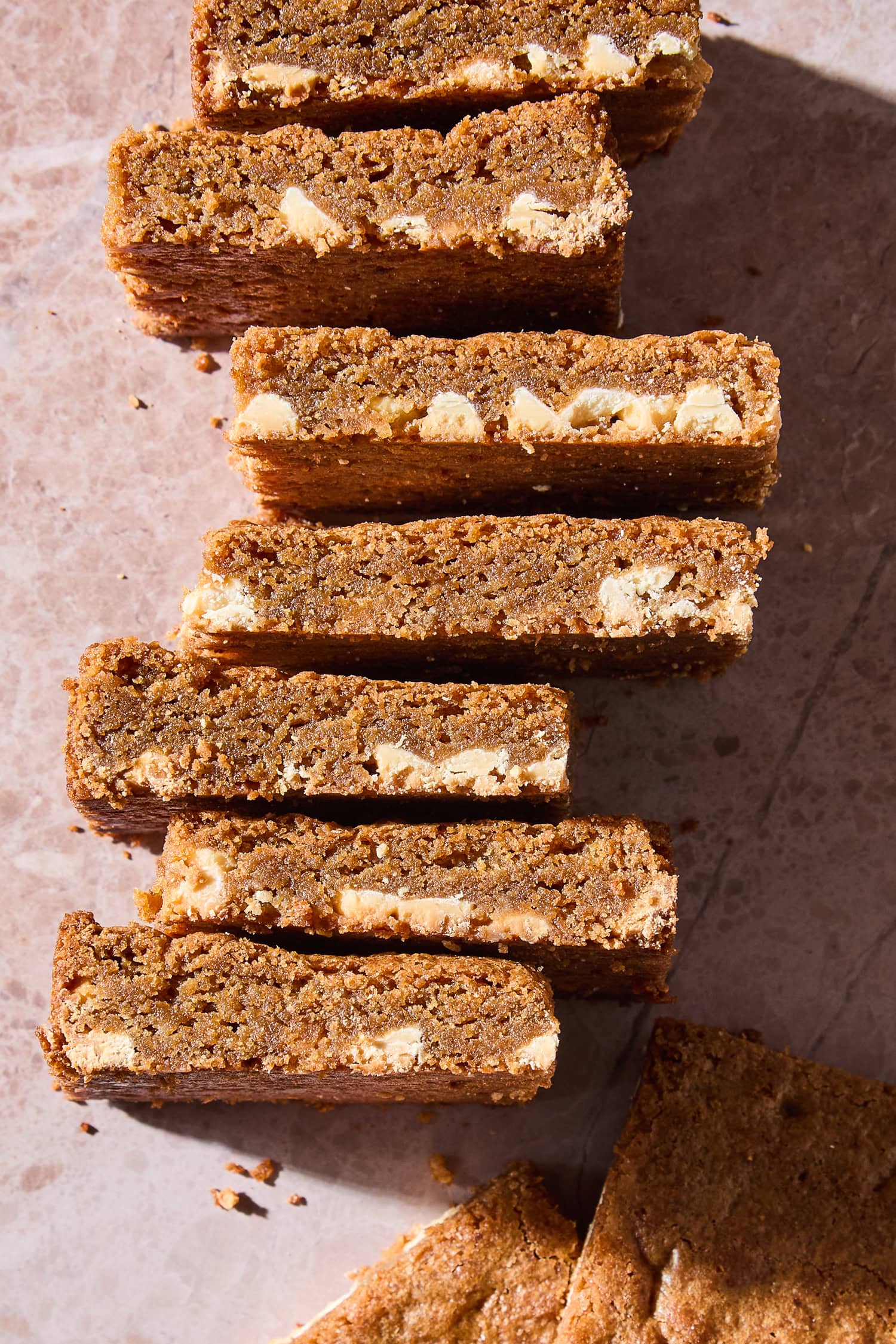 Blondies cut into squares lying sideways on a counter, revealing white chocolate inside.