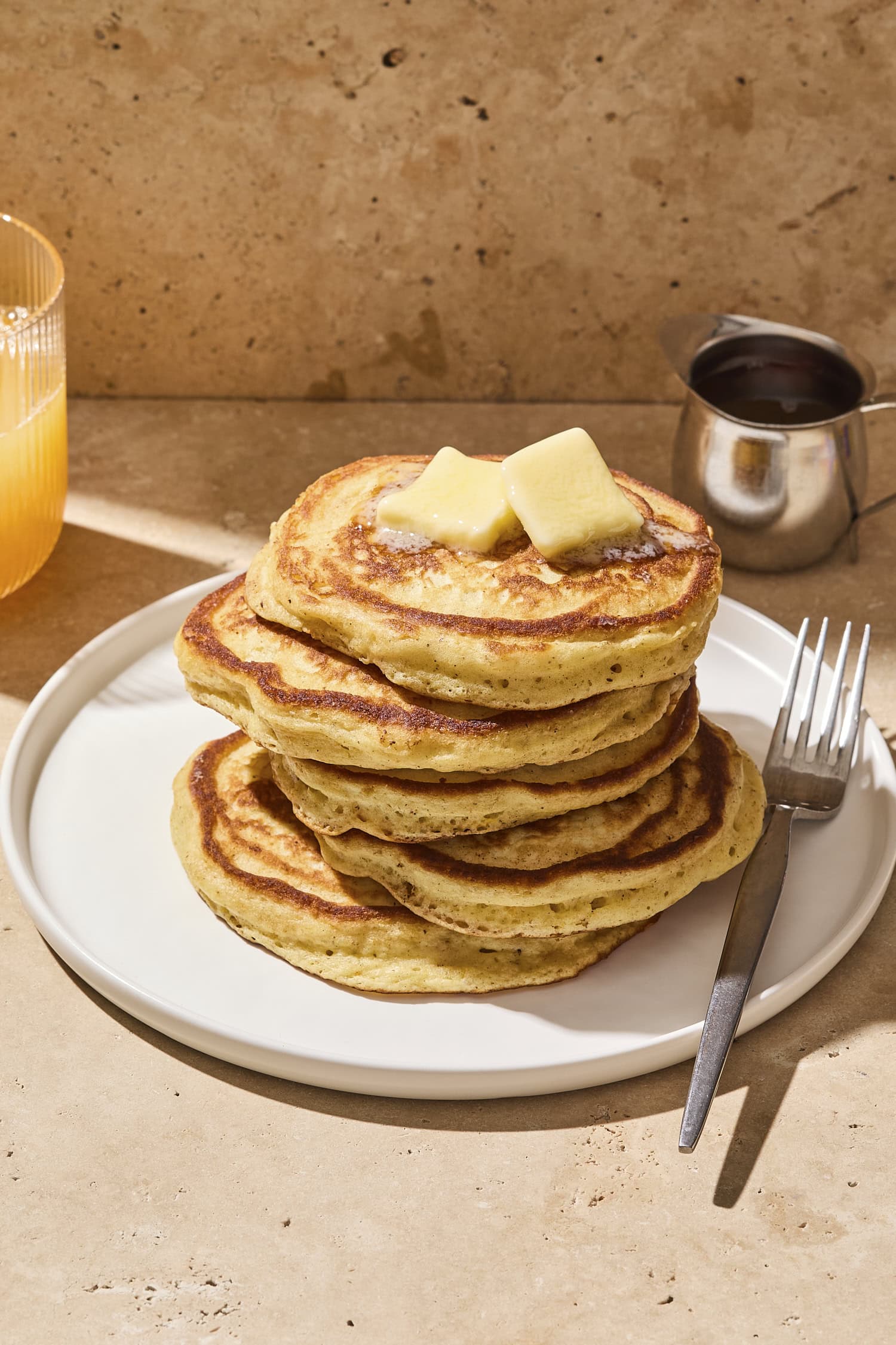 Stack of buttermilk pancakes with butter on top.
