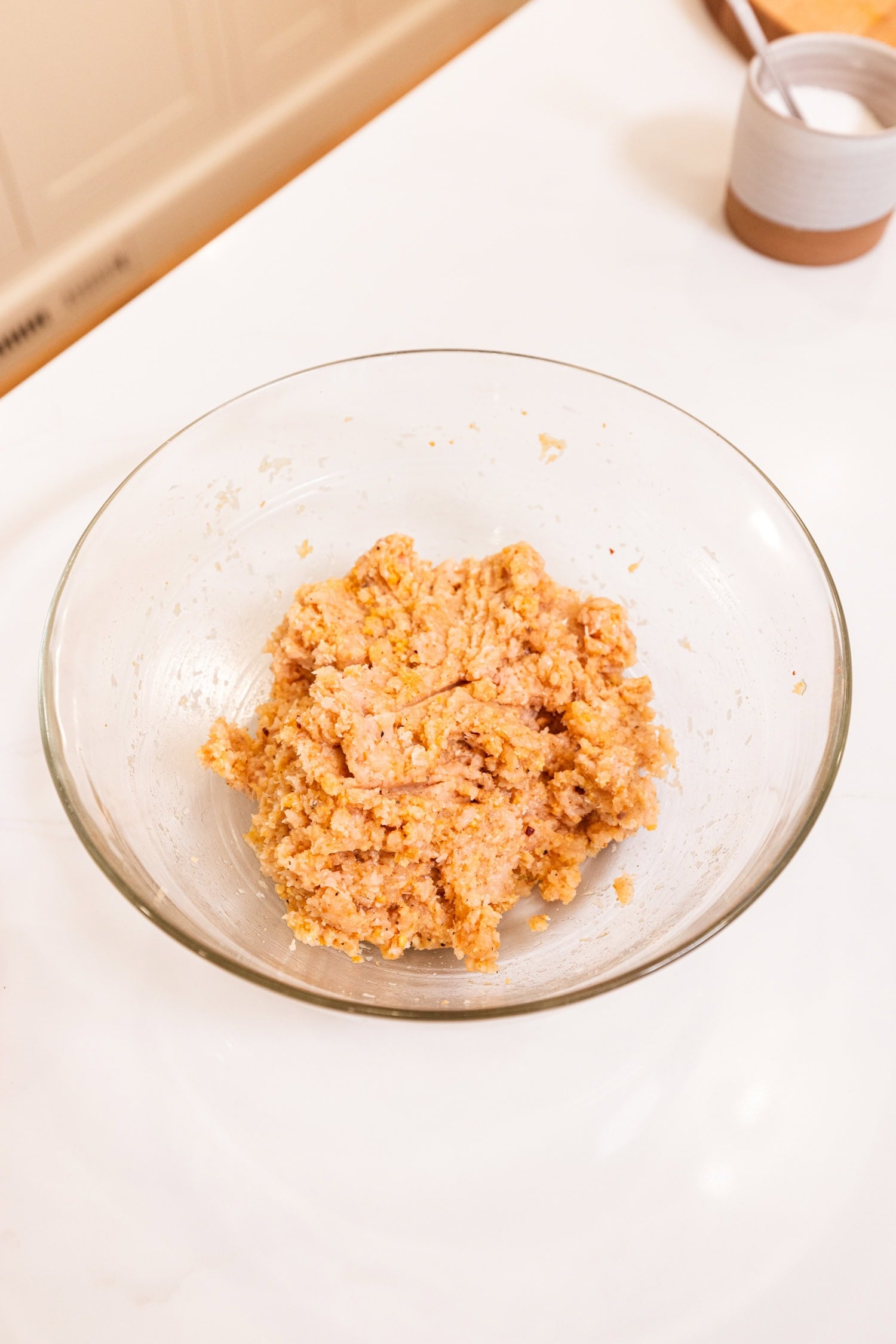 Glass bowl with meat mixture for chicken meatballs.