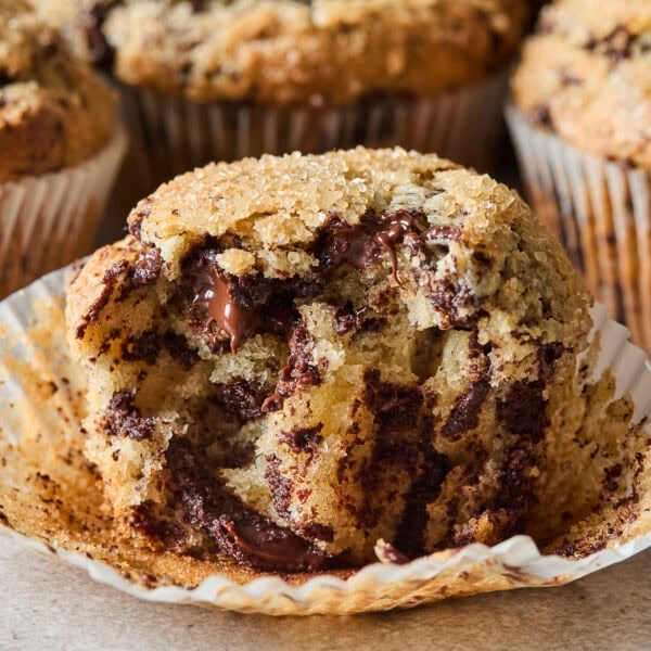 Chocolate chunk muffin broken open showing gooey chocolate.