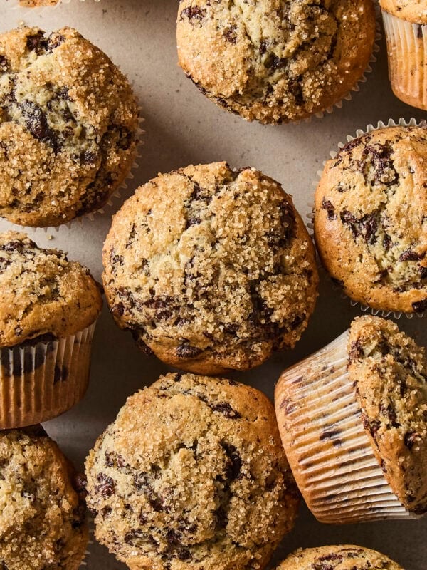 Homemade chocolate chunk muffins scattered across a counter.