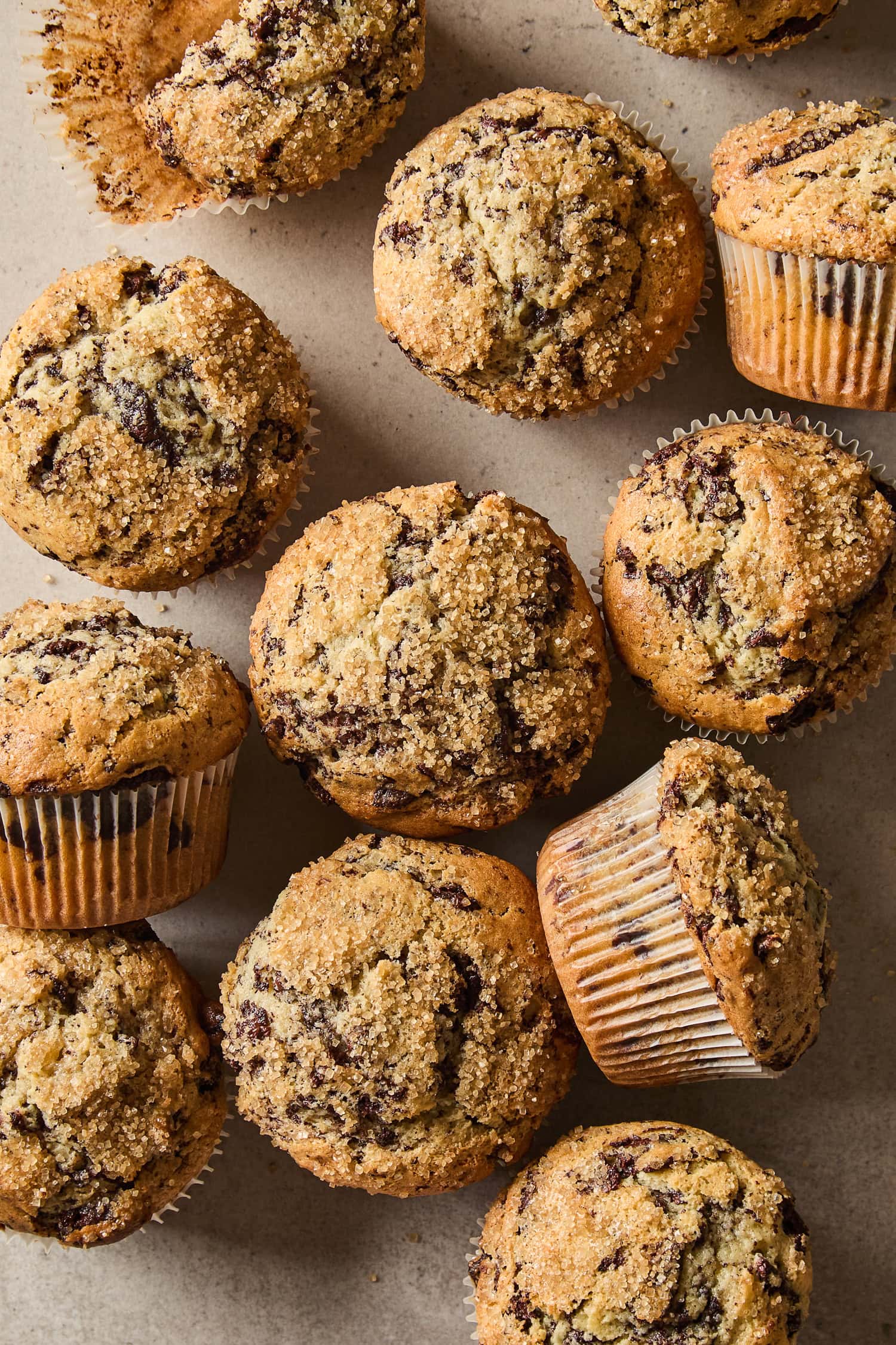 Homemade chocolate chunk muffins scattered across a counter.