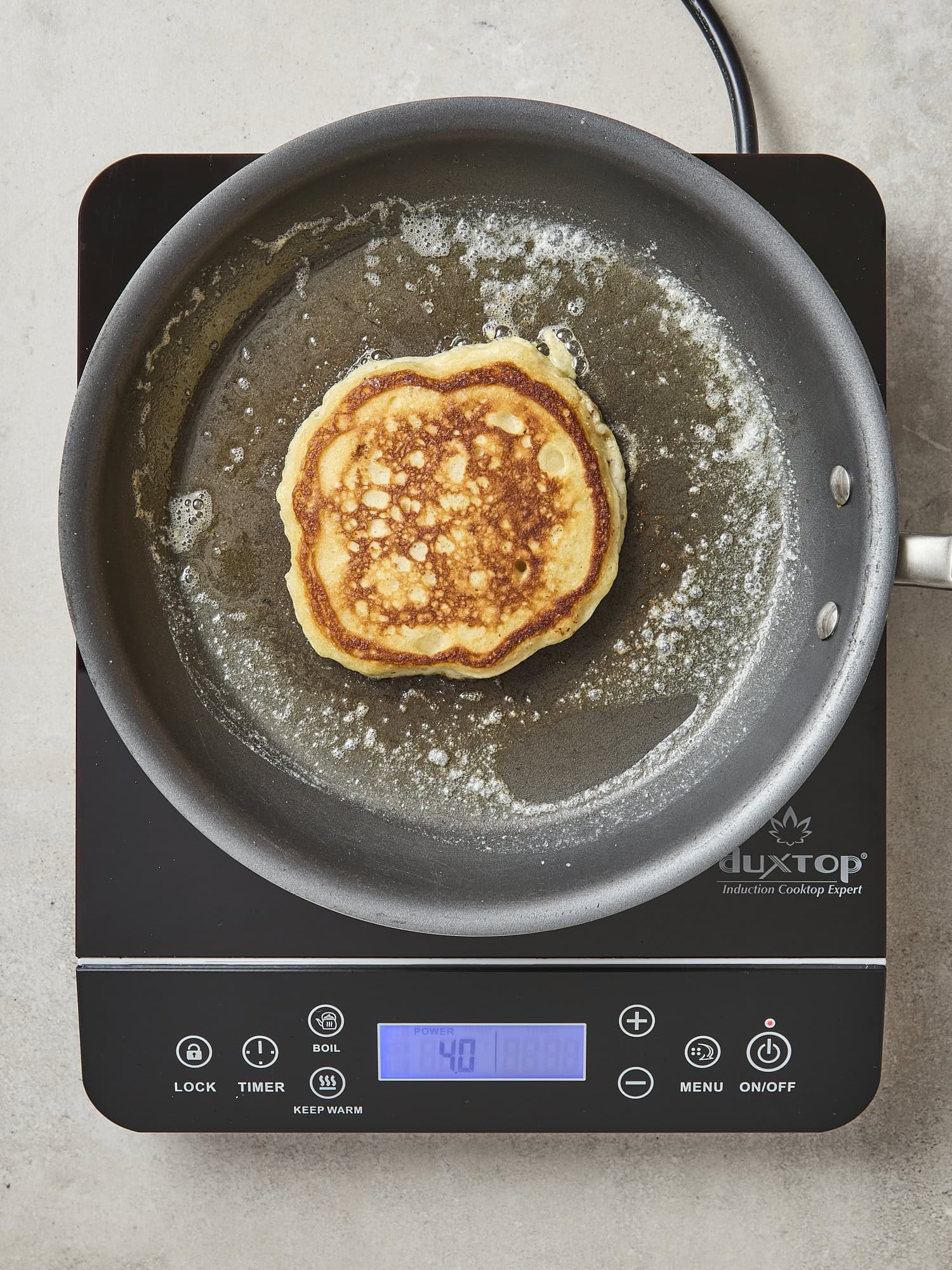 Cooked pancake with browned side in a pan.