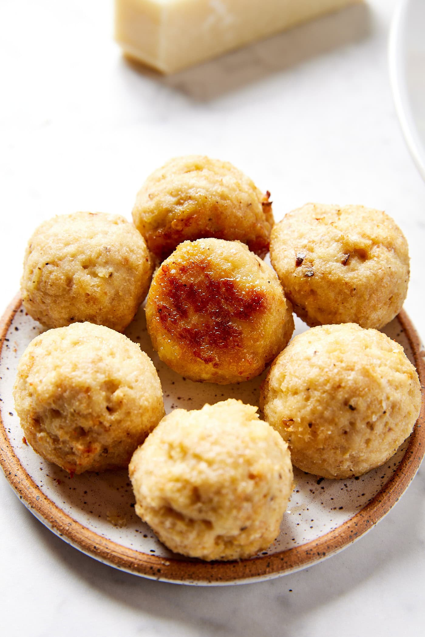 Pile of golden baked chicken meatballs on plate.