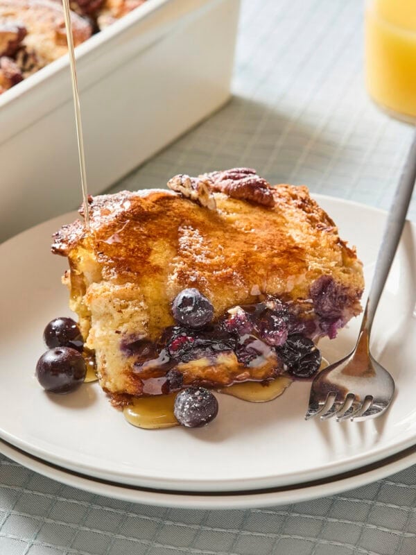 Serving of blueberry French toast with syrup pouring on top.