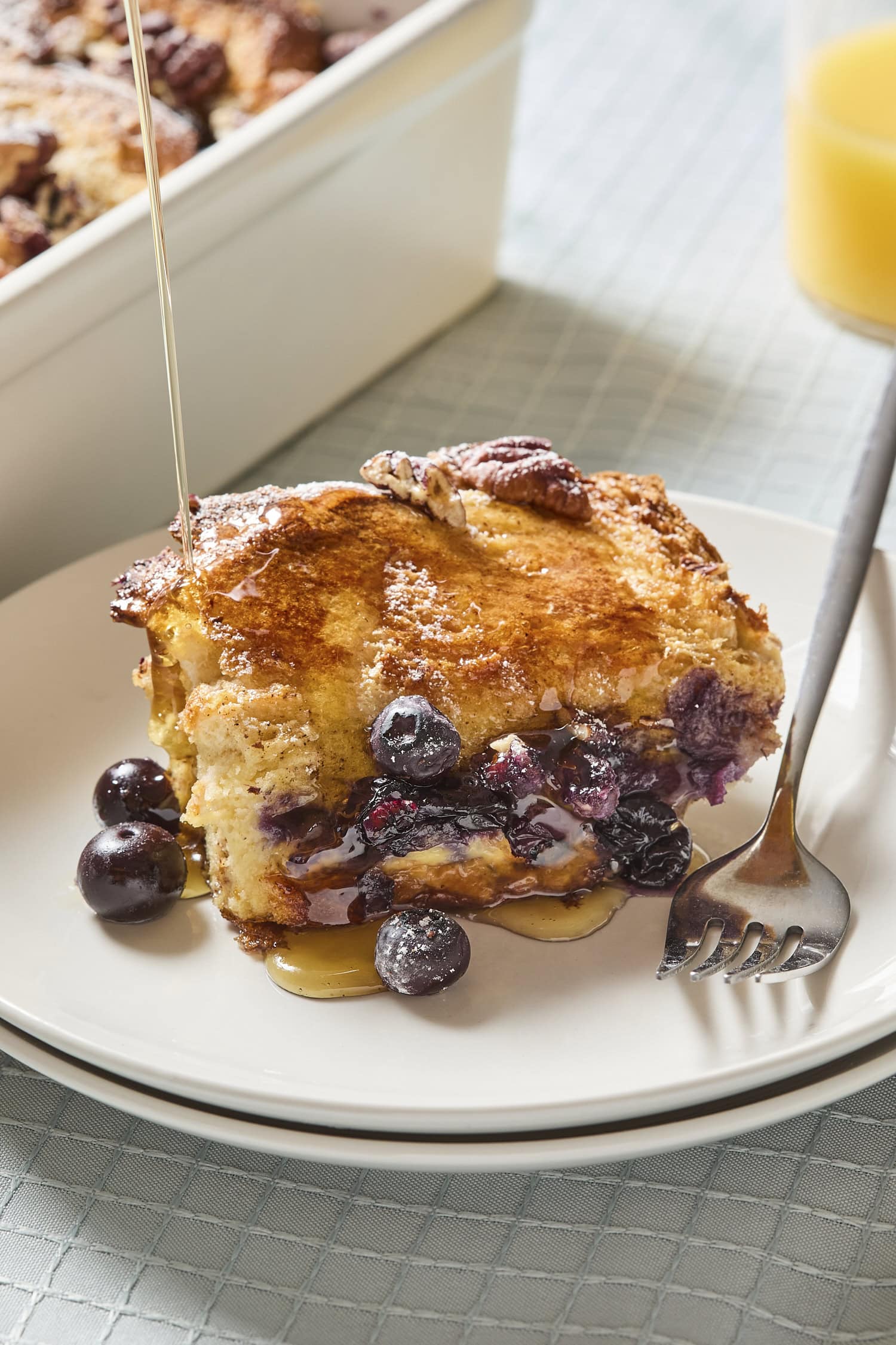 Serving of blueberry French toast with syrup pouring on top.