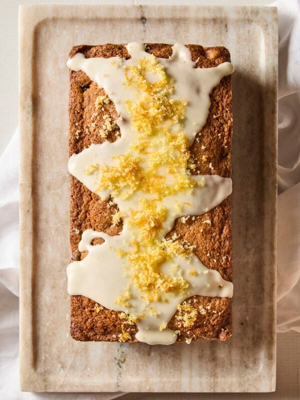 Rhubarb pound cake with glaze and orange zest on top before slicing.