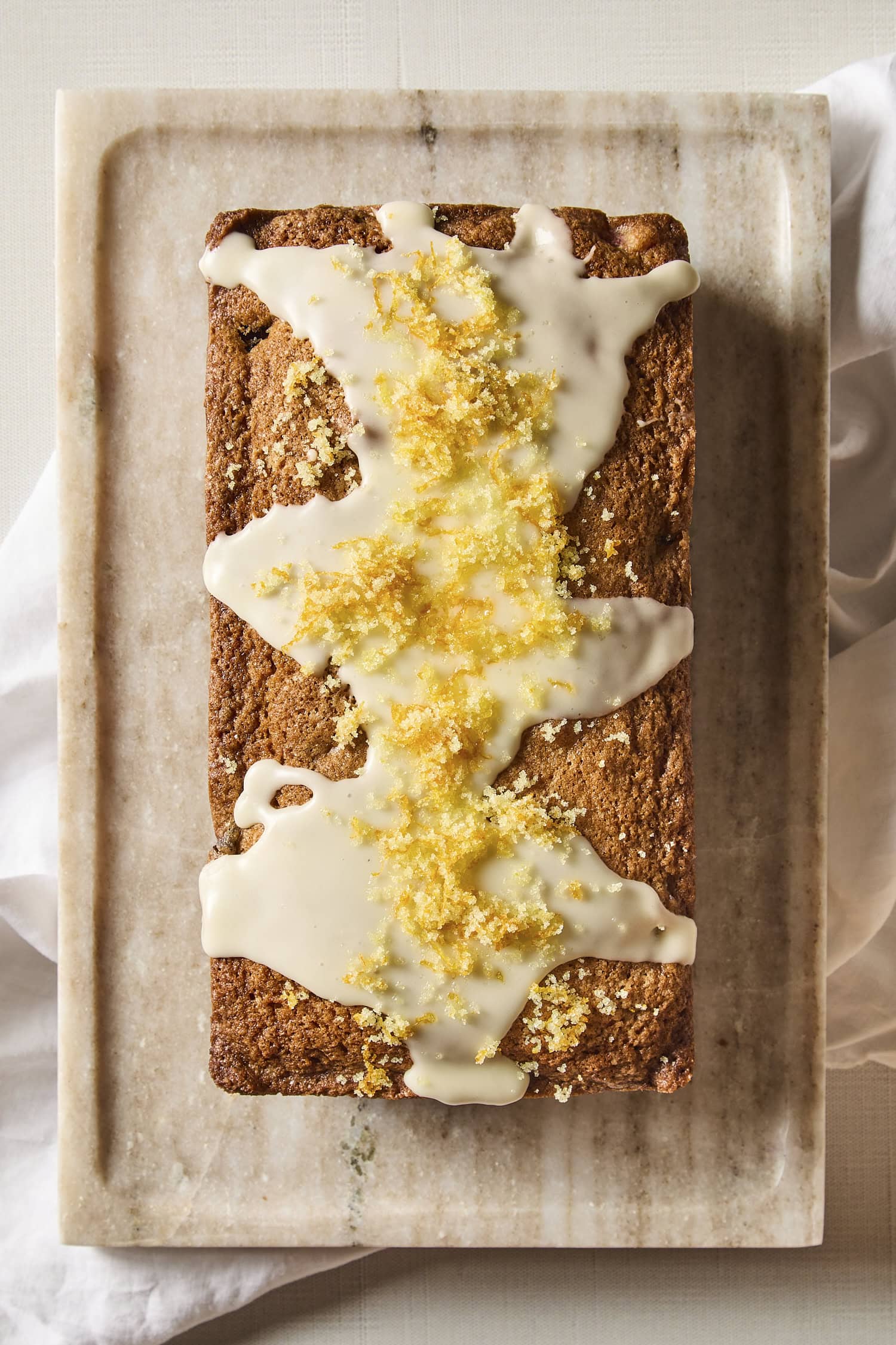 Rhubarb pound cake with glaze and orange zest on top before slicing.