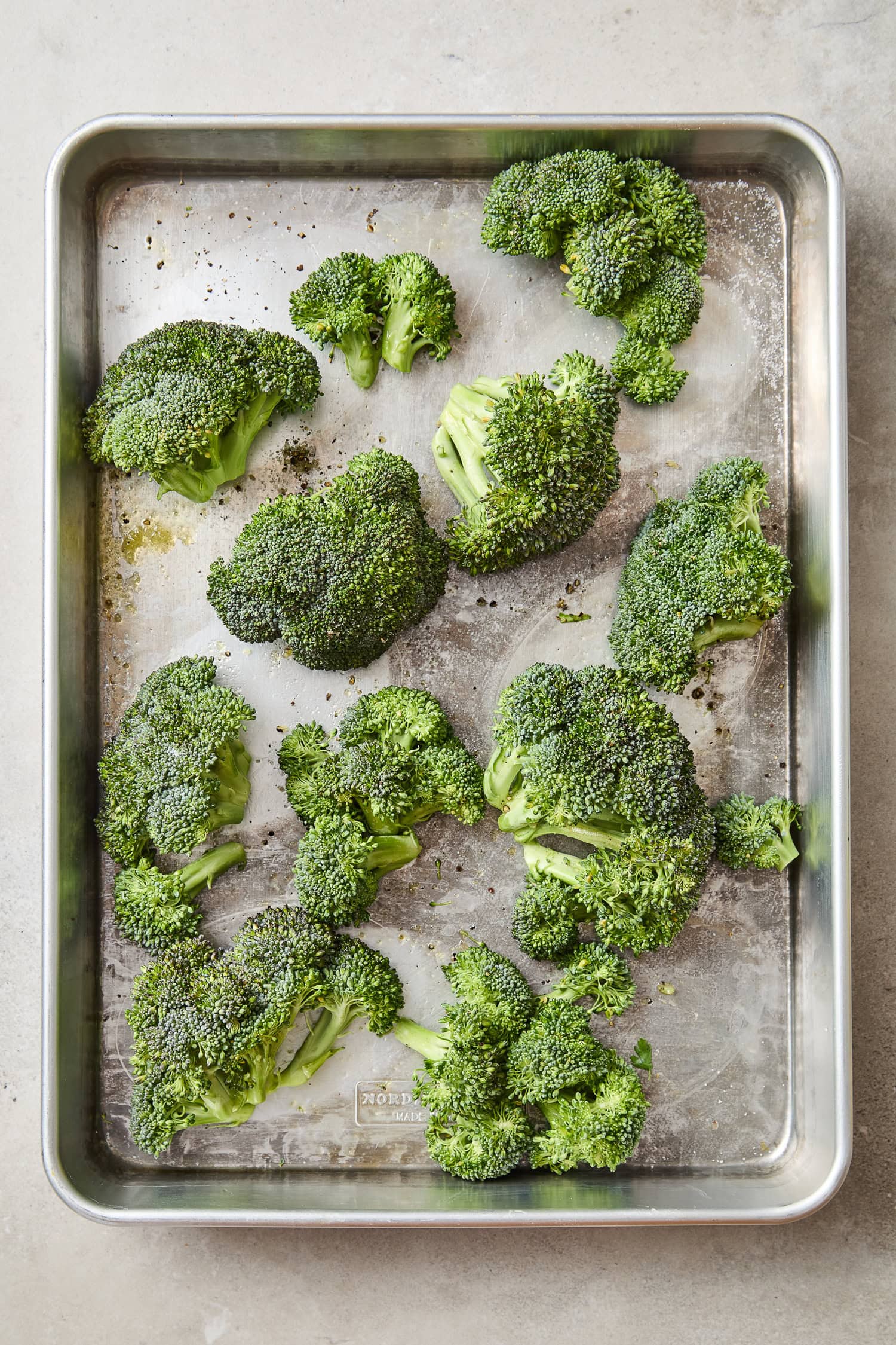 Large Broccoli florets on a sheet pan prior to grilling.