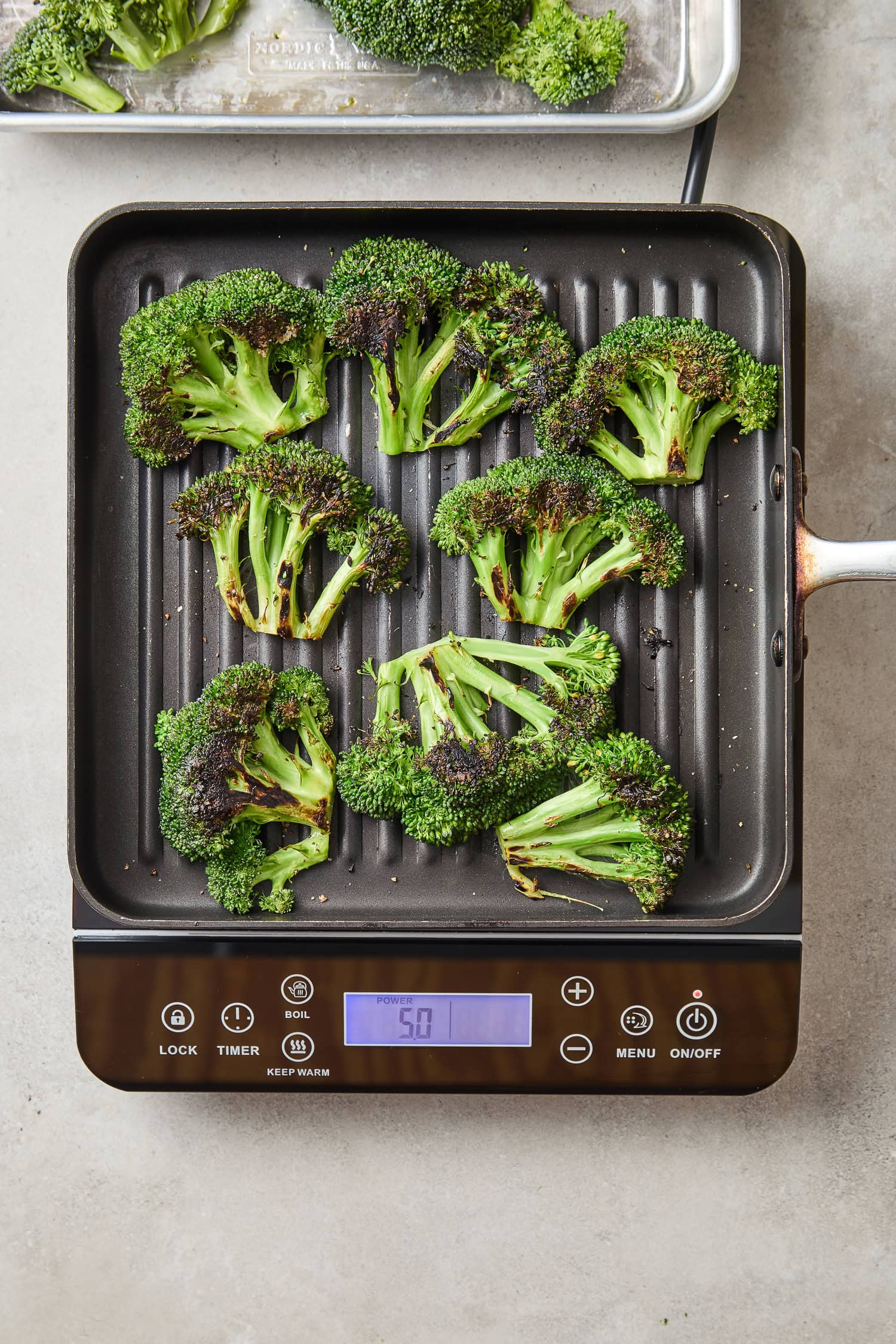 Broccoli florets roasting on a grill pan.
